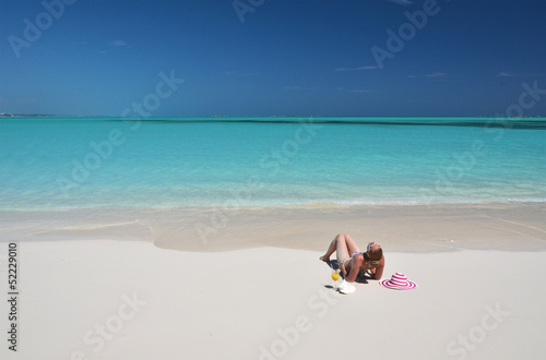 Fototapeta Naklejka Na Ścianę i Meble -  Girl with a glass of orange juice on the beach of Exuma, Bahamas