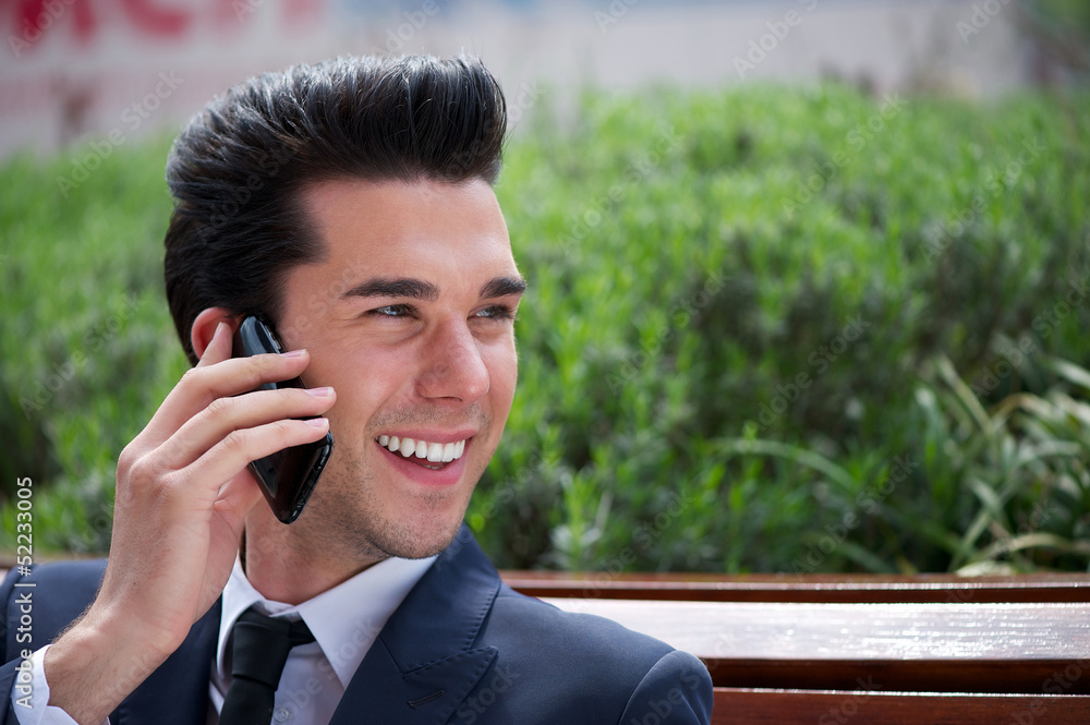 Happy businessman talking on phone outside the office Happy businessman talking on phone outside the office