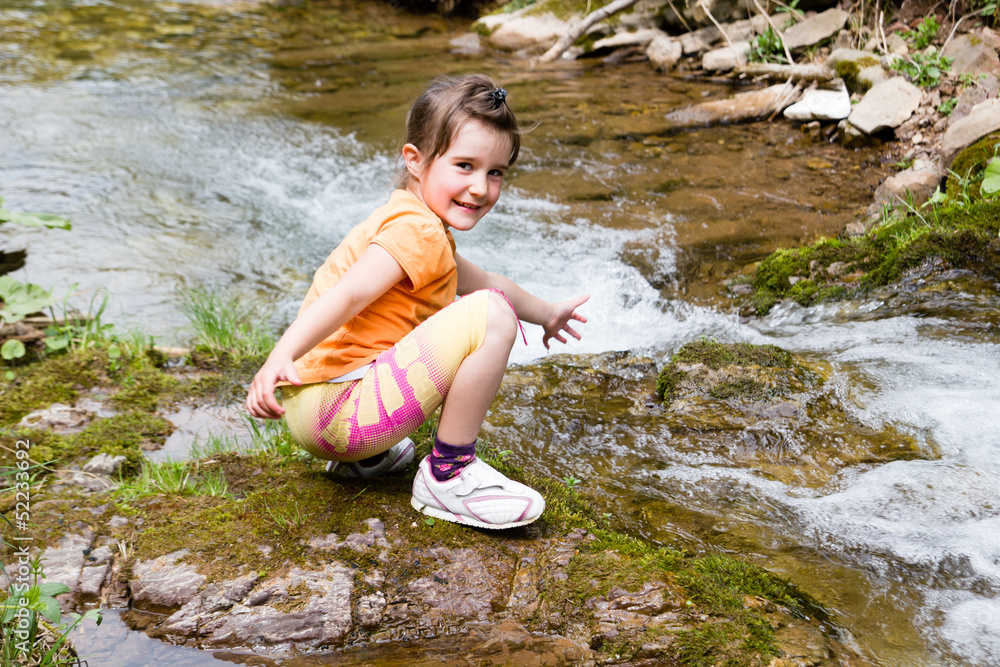 Little girl playing by a forest stream Little girl playing by a forest stream