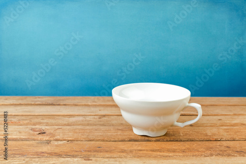 Fototapeta Naklejka Na Ścianę i Meble -  Empty coffee cup on wooden table over blue background