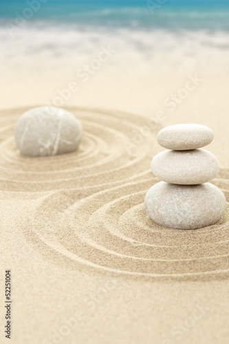 Balance zen stones in sand with sea in background