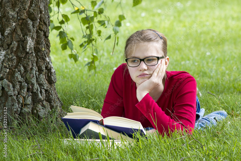 Young girl reading book in park in spring day Young girl reading book in park in spring day
