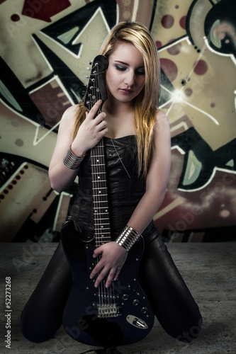 Young blonde holding a black guitar, over grafitti background © Fernando Cortés