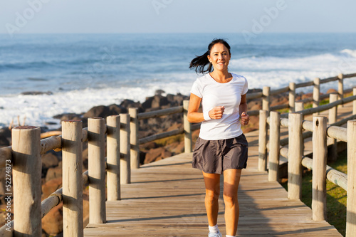 fit mid age woman jogging at the beach