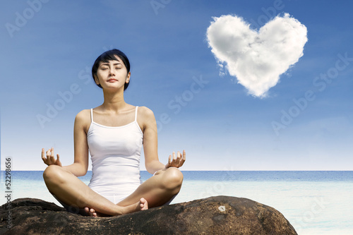 Asian woman meditating at beach