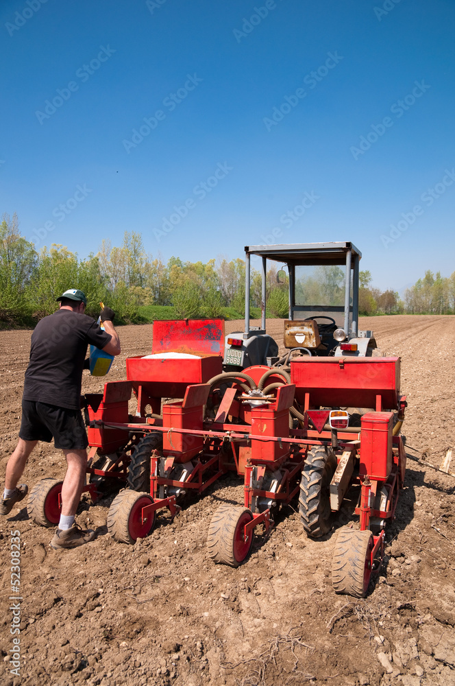 Obraz premium Farmer working with red sower on the fields