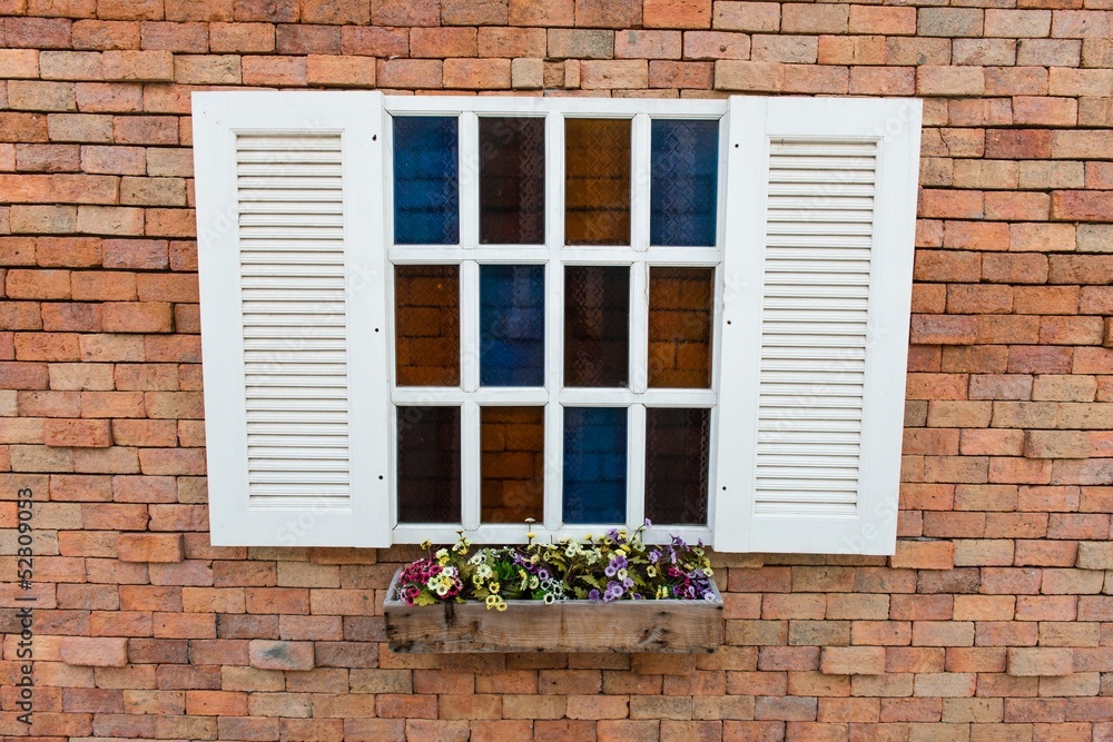 White window frame on a red brick wall with flowers