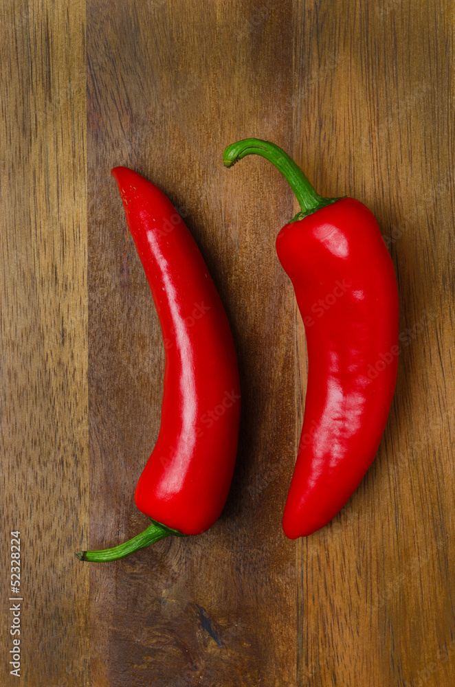 two red hot chili peppers on a wooden background