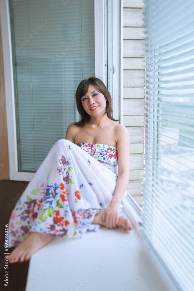 Portrait of charming girl sitting on windowsill Portrait of charming girl sitting on windowsill
