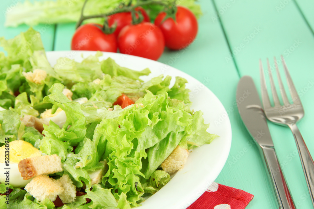 Caesar salad on blue plate, on color wooden background Caesar salad on blue plate, on color wooden background