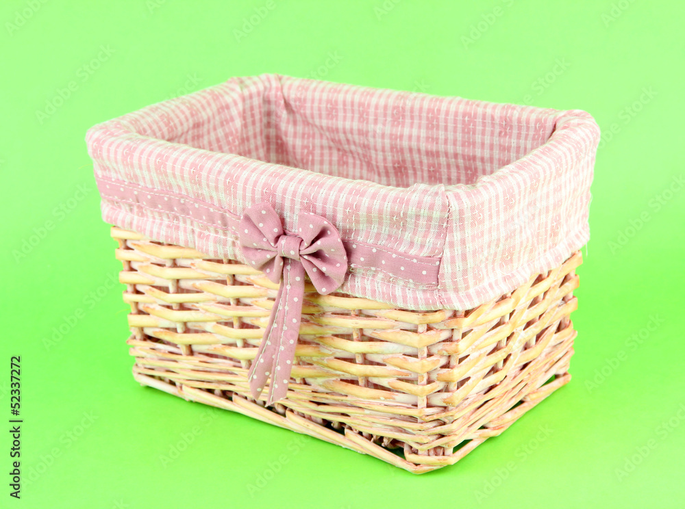 Wicket basket with pink fabric and bow, on color background Wicket basket with pink fabric and bow, on color background