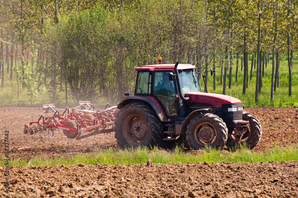 Fototapeta premium Red tractor with vibrocultor on fields side view