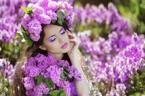 Beautiful young woman in lilac flowers  outdoors portrait