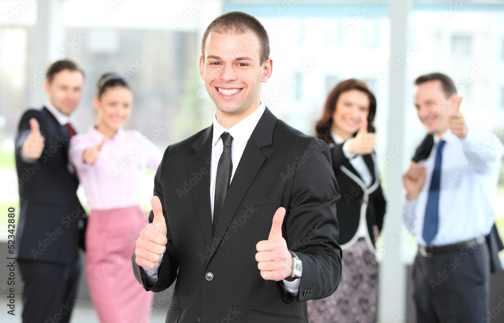 Cheerful business man with team giving you thumbs up Cheerful business man with team giving you thumbs up