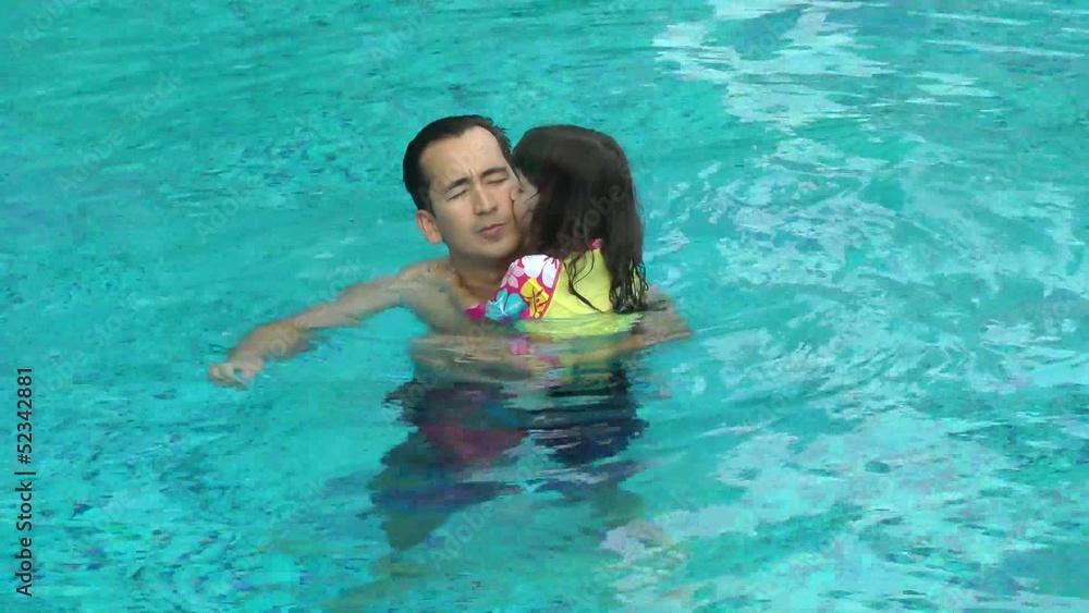 Daughter kisses her father in the pool. They are happy. Daughter kisses her father in the pool. They are happy.