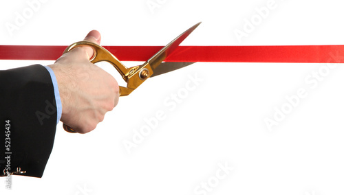Cuadro en lienzo Man's hand cutting red ribbon with pair of scissors isolated
