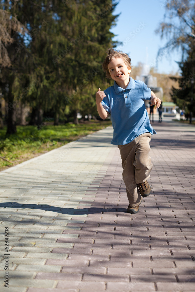 Fototapeta premium Boy running along road in park