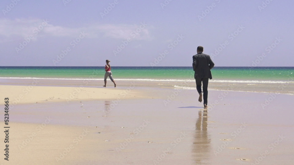 Businessman and woman jogging on the beach, super slow motion Businessman and woman jogging on the beach, super slow motion