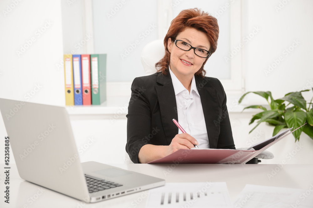 Adult businesswoman working on documents in office Adult businesswoman working on documents in office