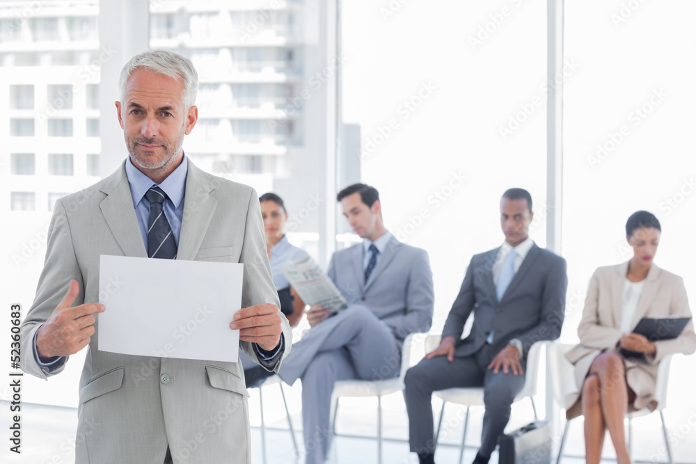 Serious businessman holding a blank notice Serious businessman holding a blank notice