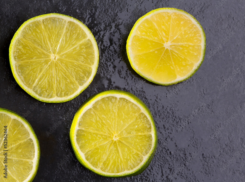 Fresh lima slices with water drops on black Fresh lima slices with water drops on black