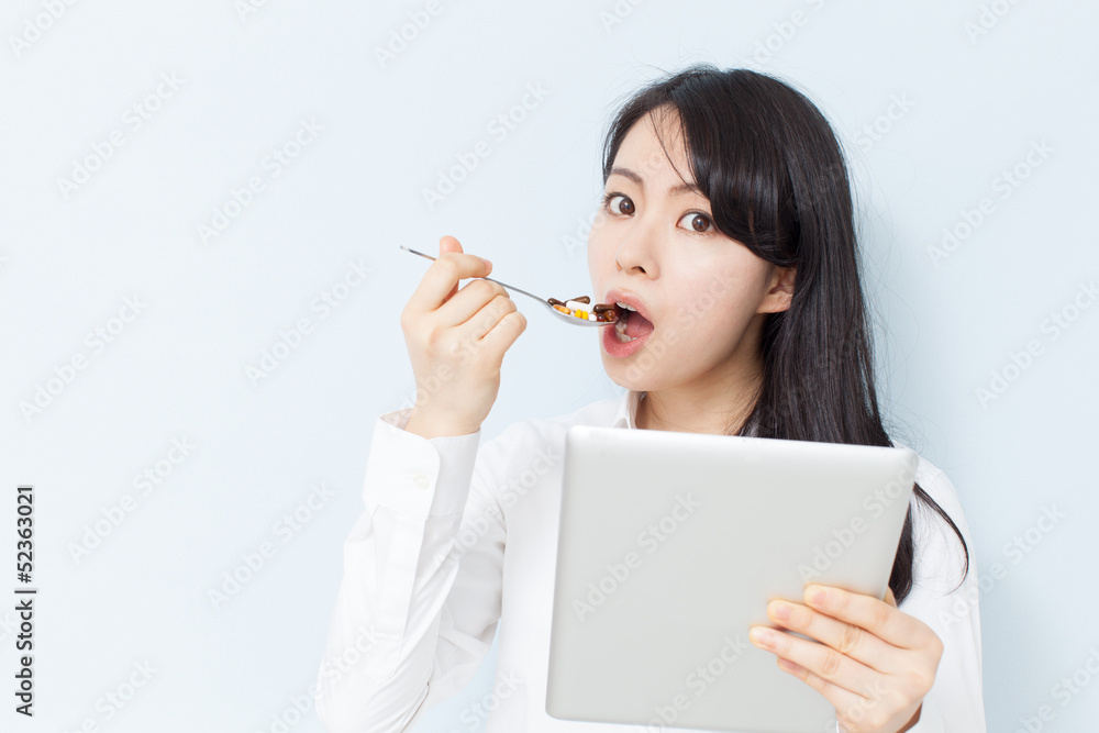 タブレットPCを見ながらサプリメントを食べる女性 タブレットPCを見ながらサプリメントを食べる女性