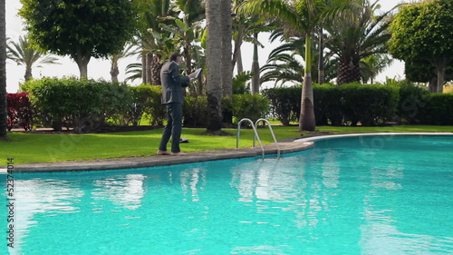 Angry businessman walking with cellphone by the poolside