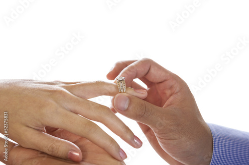 Young Adult Male hand putting engagement ring on Female finger