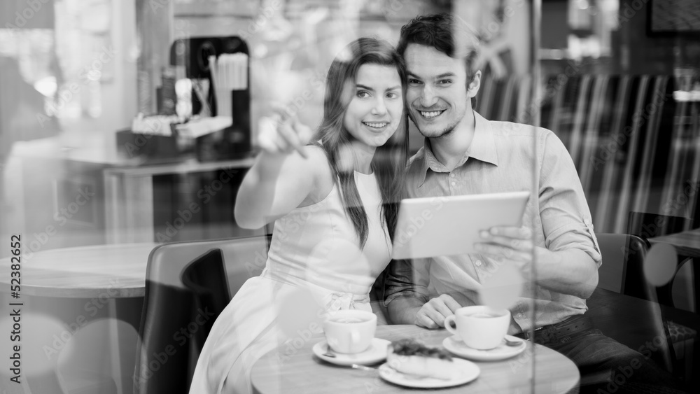 Happy couple in cafe holding digital tablet Happy couple in cafe holding digital tablet