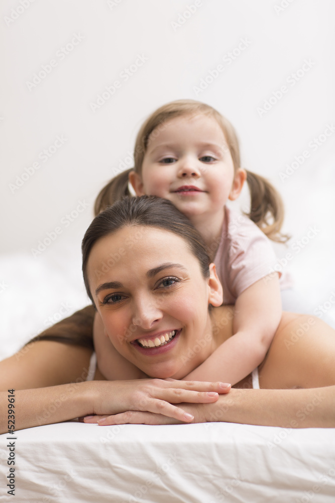 Daughter hugging her mother on the white bed