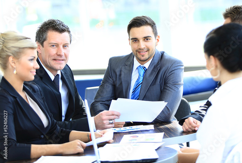 Smiling young man sitting at a business meeting with colleagues