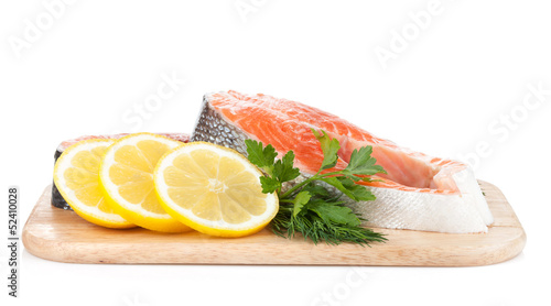 Salmon steaks on cutting board with lemons and herbs