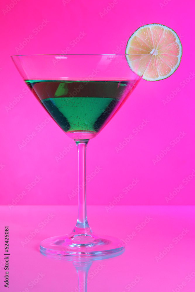 Green cocktail in martini glass on pink background Green cocktail in martini glass on pink background