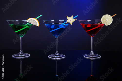 Alcoholic cocktails in martini glasses on dark blue background