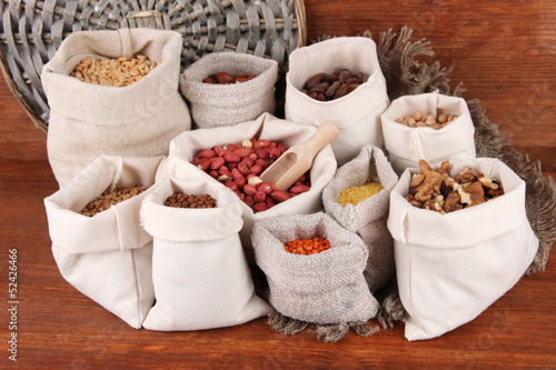 Different kinds of beans in sacks on wooden background © Africa Studio