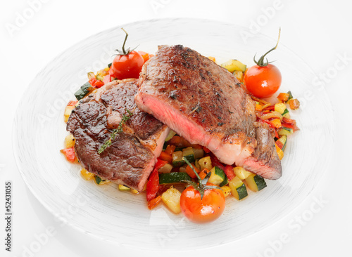 Medium fried steak with vegetables shot on light background