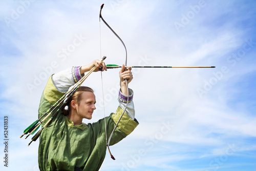 Young archer with bow and arrows in medieval costume aiming
