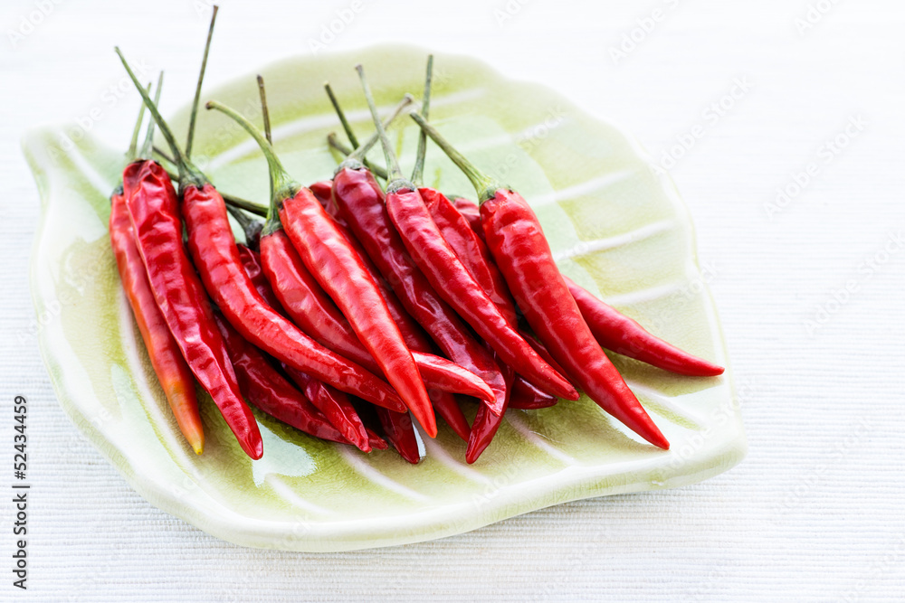 Red chili peppers on plate over light background Red chili peppers on plate over light background