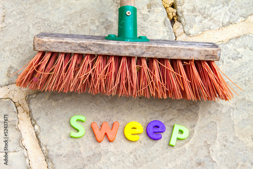 Garden brush on patio floor with the word sweep spelt out undern