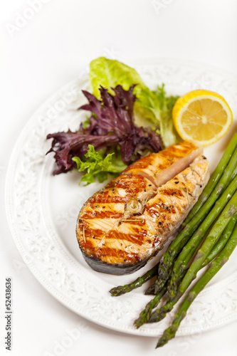 Grilled salmon steak with asparagus, lemon and salad