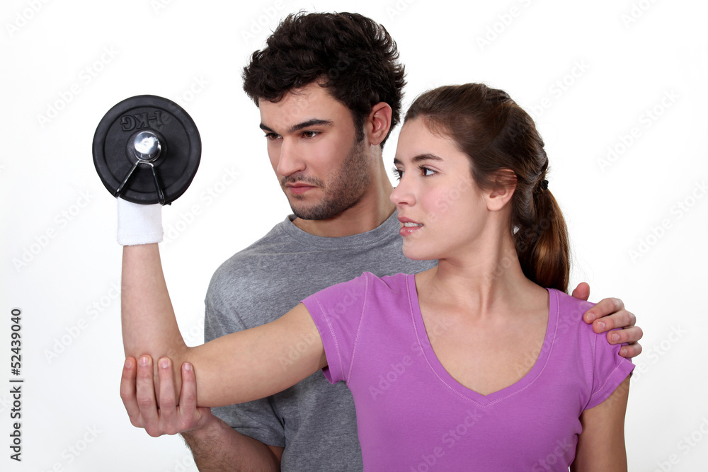 Coach helping a client lift a dumbbell Coach helping a client lift a dumbbell