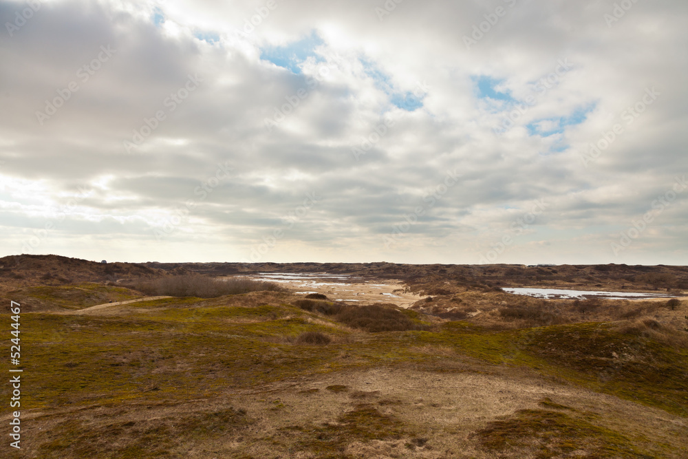 Grassy dune landscape with little lakes and blue cloudy sky. Grassy dune landscape with little lakes and blue cloudy sky.