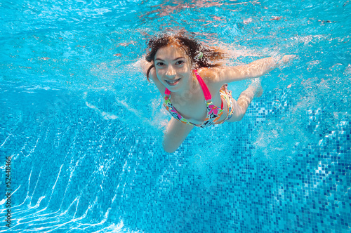 Happy active child swims underwater in pool