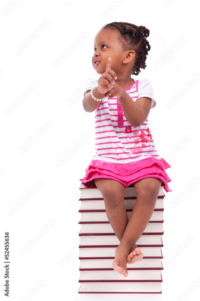 Cute black african american little girl seated in a stack of boo Cute black african american little girl seated in a stack of boo