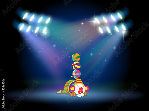 A clown doing some tricks at the center of the stage