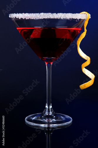 Red cocktail in martini glass on dark blue background
