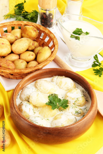 Tender young potatoes with sour cream and herbs in wooden bowl