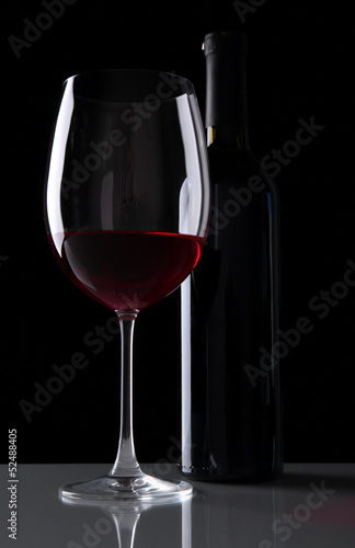 Glass of wine with bottle on black background
