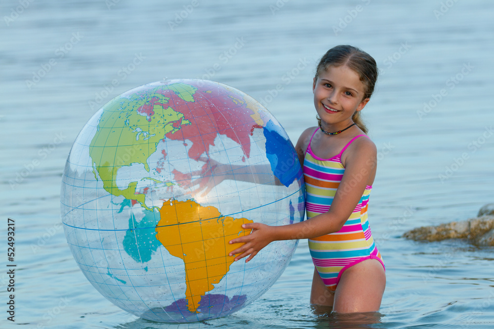 Lovely girl playing in the sea with inflatable globe ball. Lovely girl playing in the sea with inflatable globe ball.