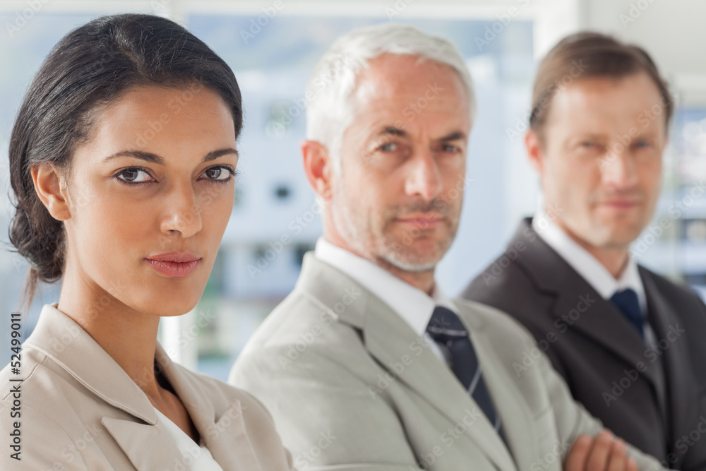 Serious businesswoman smiling with colleagues behind Serious businesswoman smiling with colleagues behind